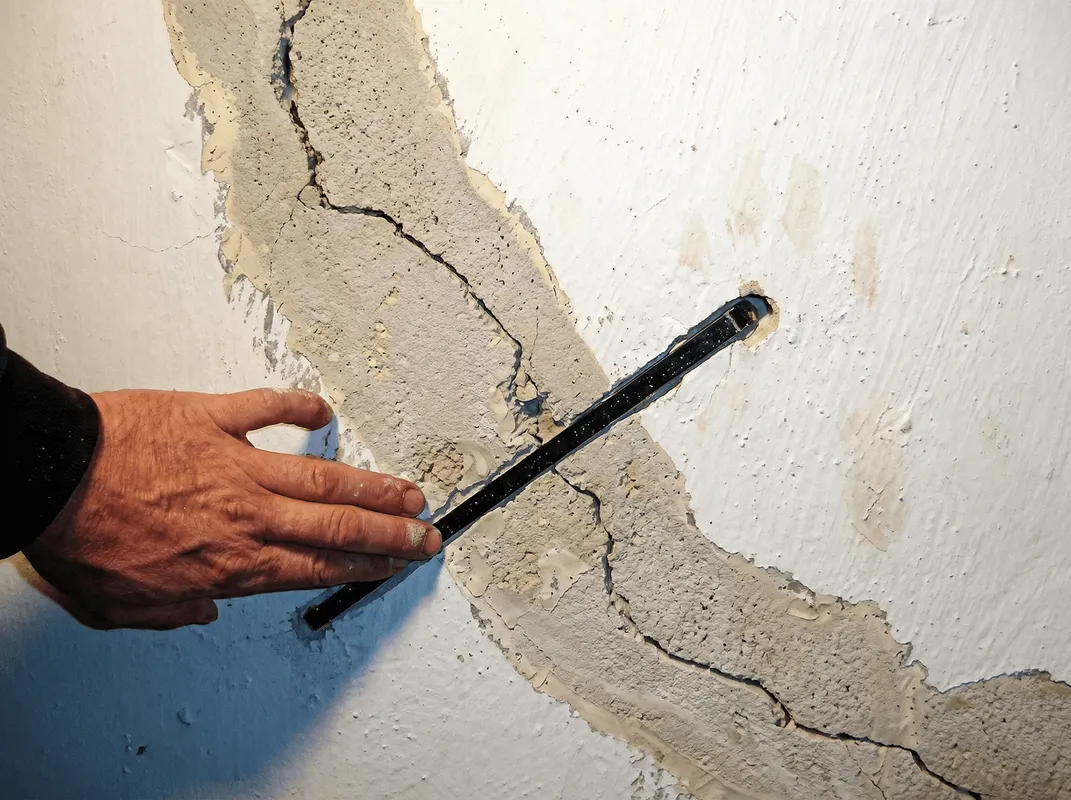 A wall with a large crack is being inspected by a professional in Chicago, IL